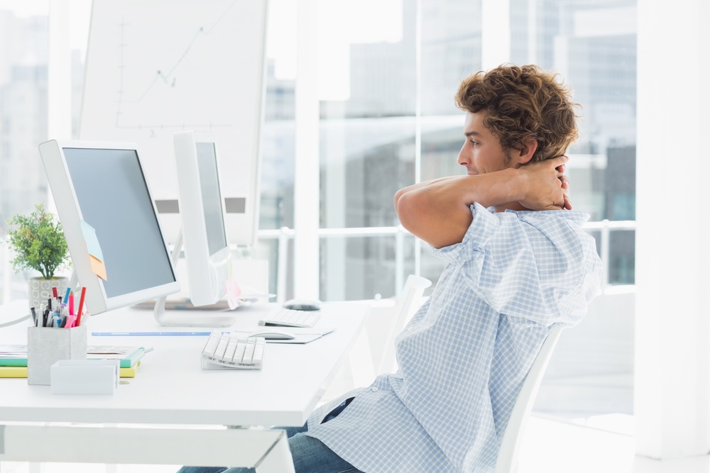 Side view of a casual young business man using computer in a bright office.jpeg Side view of a casual young business man using computer in a bright office.jpeg